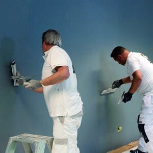 Maler glätten eine magnetische Wand mit der Glättkelle Zwei Maler glätten eine magnetische Wand mit einer Edelstahl-Glättkelle