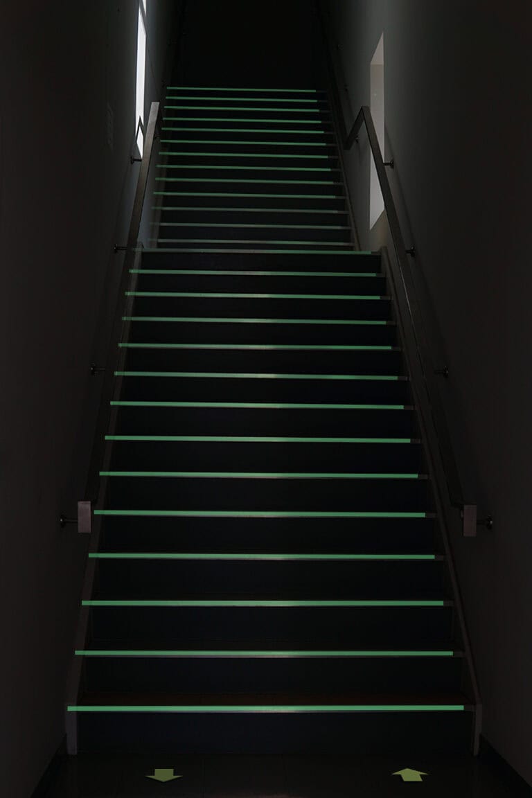 Dunkle Treppe mit leuchtenden grünen Sicherheitsstreifen aus GlowPaint
