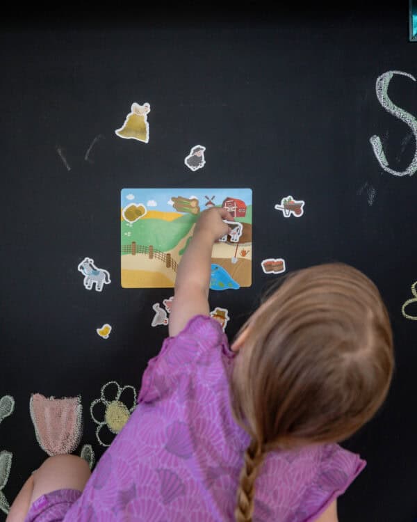 Kind spielt mit Magneten an der Wand Kind legt magnetische Spielfiguren auf ein Magnetspielbrett an einer magnetischen Tafelwand