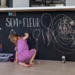 Kind malt mit Kreide an einer mit SchultafelFarbe gestrichenen Wand